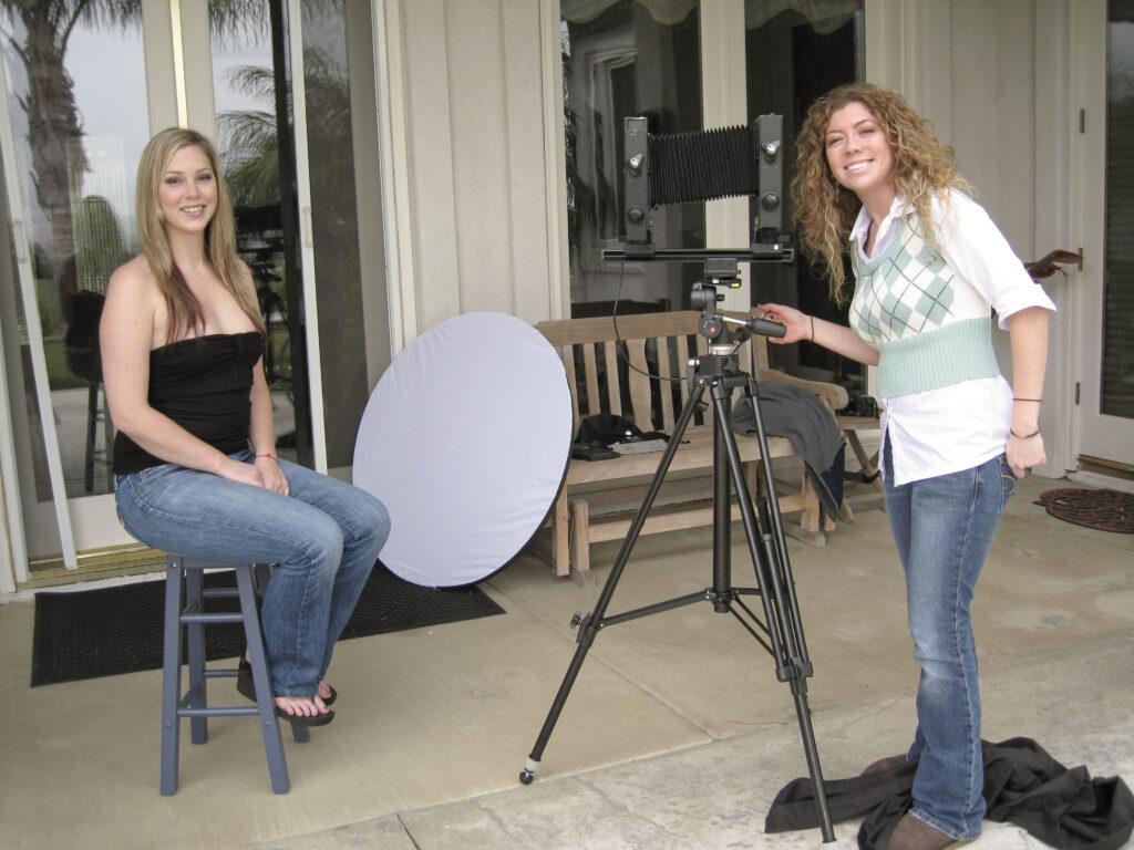 Jaclyn smiling while preparing a large-format camera setup for a portrait session outdoors, capturing her early days exploring portrait photography and developing her style.