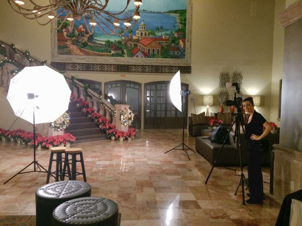 Jaclyn confidently standing next to her professional lighting setup in a beautifully decorated event space, highlighting her experience and versatility as a photographer.