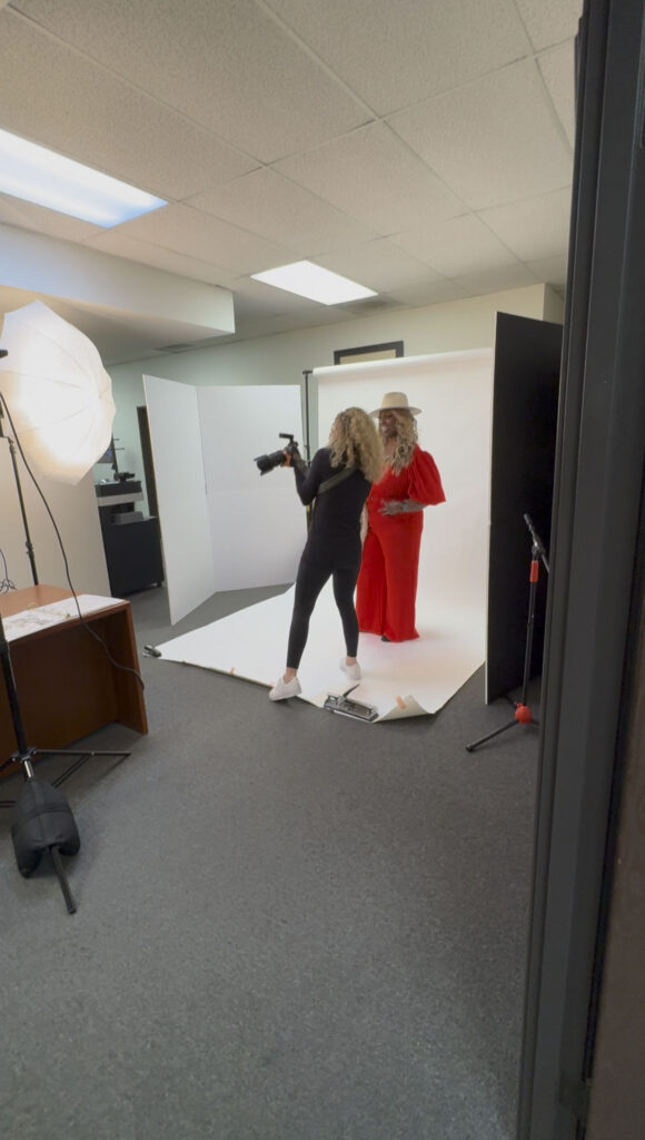 Jaclyn capturing branding photos in her studio setup, guiding and connecting with a client dressed in vibrant red, creating authentic brand visuals.