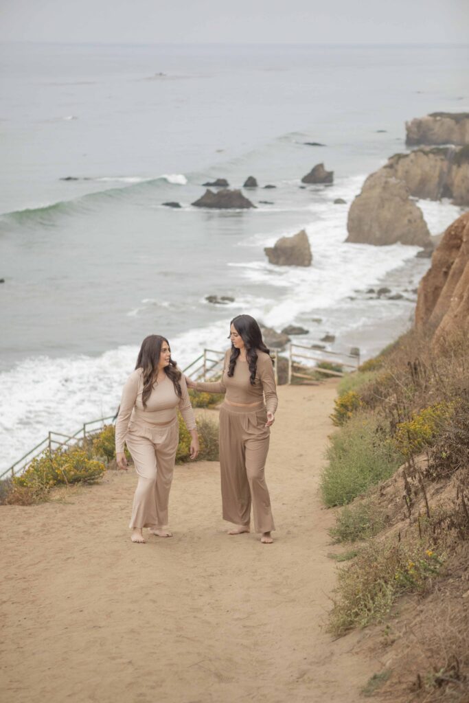 Kristine King walking barefoot along a beachside trail, engaging in heartfelt conversation during a healing brand session.
