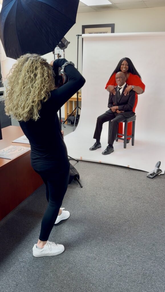 Denise Carter and her husband posing together in formal attire against a white studio background.
