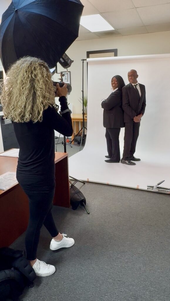 Denise Carter and her husband posing together in formal attire against a white studio background.