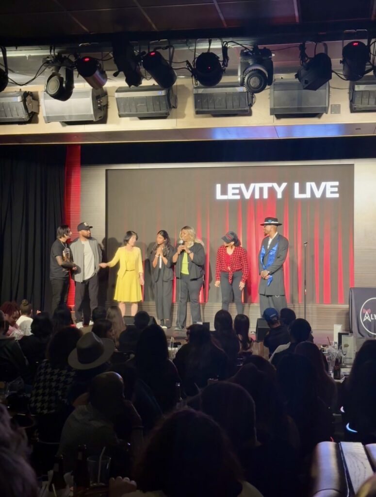 Denise Carter performing stand-up comedy on stage at Levity Live in Oxnard with a live audience.